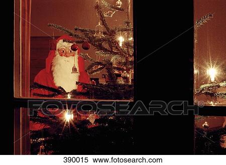 View through a window of Santa Claus standing behind an illuminated Christmas tree View Large Photo Image Stock Photography - View through a window of Santa Claus standing behind an illuminated Christmas tree. Fotosearch
