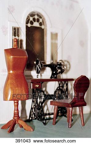 Stock Image - Miniature dressmaker's model and sewing machine in a doll's house. Fotosearch
