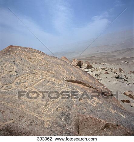 Stock Image - Carvings on rocks in barren landscape, near Peru. Fotosearch