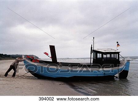 Man pushing a boat into the sea View Large Photo Image Stock Image - Man pushing a boat into the sea. Fotosearch