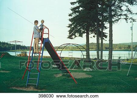 A mother standing at the top of a slide with her young son View Large Photo Image Stock Image - A mother standing at the top of a slide with her young son. Fotosearch