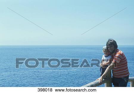 Father holding his son at an observation point overlooking the ocean View Large Photo Image Stock Photo - Father holding his son at an observation point overlooking the ocean. Fotosearch