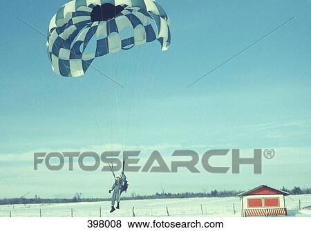 Man landing in a parachute on a snow covered field View Large Photo Image Stock Photo - Man landing in a parachute on a snow covered field. Fotosearch