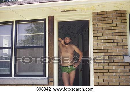 Stock Image - Man standing in a doorway wearing racing briefs. Fotosearch