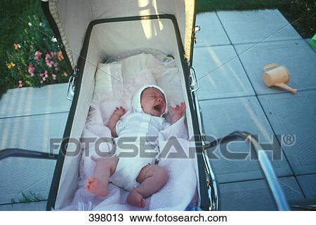 Stock Image - Newborn baby yawning in a pram. Fotosearch