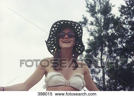 Portrait of a young woman wearing a bikini top, hat and sunglasses View Large Photo Image Stock Photography - Portrait of a young woman wearing a bikini top, hat and sunglasses. Fotosearch