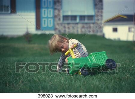 Stock Image - Young boy falling off a ride-on plastic toy. Fotosearch