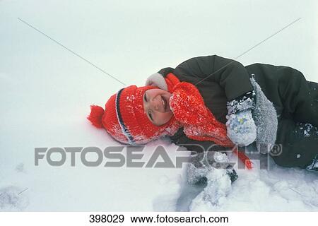 Young boy lying down on snow View Large Photo Image Stock Photo - Young boy lying down on snow. Fotosearch