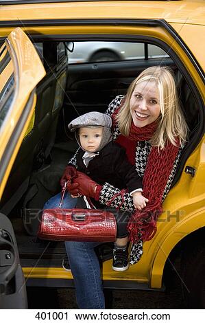 Stock Image - Mother and child getting out of a yellow cab. Fotosearch