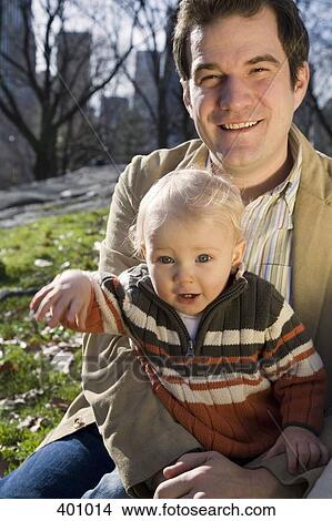 Young boy sitting in park with his father View Large Photo Image Picture - Young boy sitting in park with his father. Fotosearch