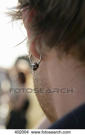 Man wearing a scull earring View Large Photo Image Picture - Man wearing a scull earring. Fotosearch