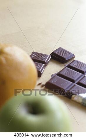 An apple, orange, and some chocolate View Large Photo Image Picture - An apple, orange, and some chocolate. Fotosearch