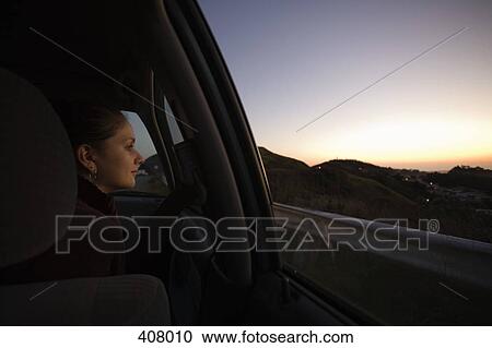 Young woman looking through car window View Large Photo Image Stock Image - Young woman looking through car window. Fotosearch