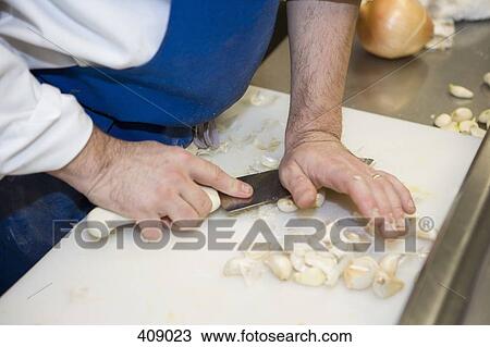 Chef squashing cloves of garlic View Large Photo Image Stock Image - Chef squashing cloves of garlic. Fotosearch