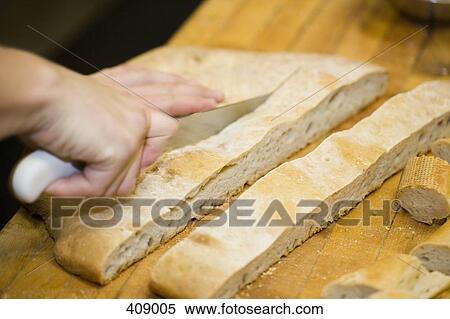 Person slicing bread on a cutting board View Large Photo Image Stock Photography - Person slicing bread on a cutting board. Fotosearch