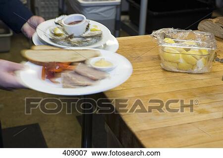 Waiter picking up plates of food from a restaurant kitchen View Large Photo Image Stock Photo - Waiter picking up plates of food from a restaurant kitchen. Fotosearch