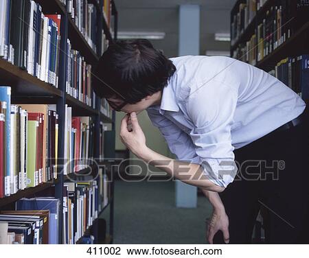 Student looking at books in a library View Large Photo Image Stock Image - Student looking at books in a library. Fotosearch