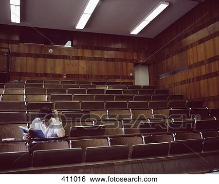 University student sitting in an empty lecture hall reading a text book View Large Photo Image Stock Photograph - University student sitting in an empty lecture hall reading a text book. Fotosearch