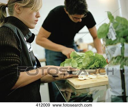 Stock Photo - Young couple preparing food in a kitchen. Fotosearch