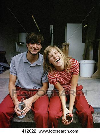 Young couple sitting together and laughing during a break View Large Photo Image Stock Image - Young couple sitting together and laughing during a break. Fotosearch