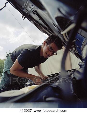 Young man checking a car battery View Large Photo Image Stock Photo - Young man checking a car battery. Fotosearch