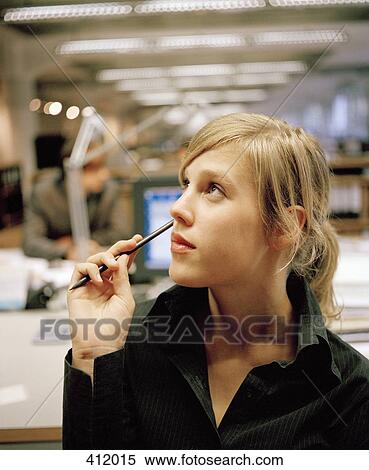Young woman looking away whilst sitting at an office desk View Large Photo Image Stock Photography - Young woman looking away whilst sitting at an office desk. Fotosearch