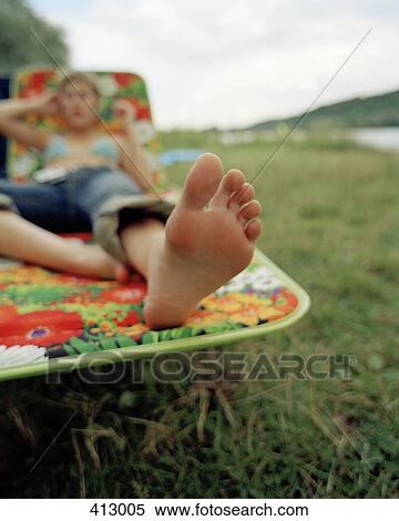 Stock Photography - A woman lying on a sun lounger. Fotosearch