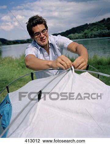 Stock Image - A young man putting up a tent. Fotosearch