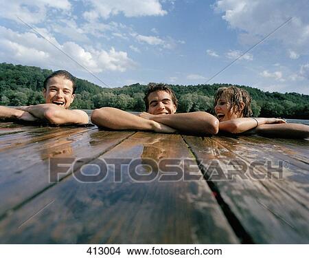 Friends resting on a wooden jetty View Large Photo Image Picture - Friends resting on a wooden jetty. Fotosearch