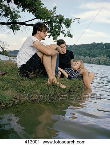 Three friends sitting at the edge of a lake View Large Photo Image Stock Image - Three friends sitting at the edge of a lake. Fotosearch