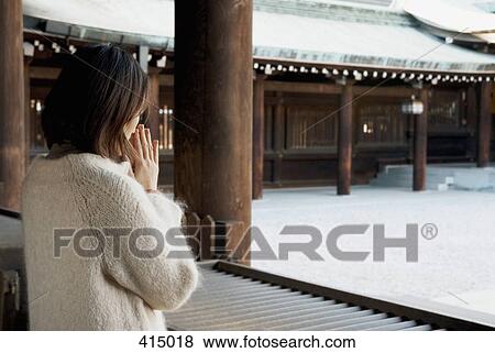 Stock Photo - A woman praying in a temple. Fotosearch