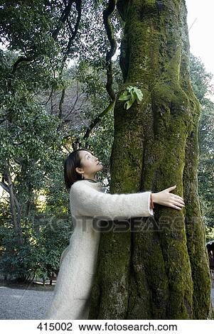 Stock Image - Woman embracing a tree. Fotosearch