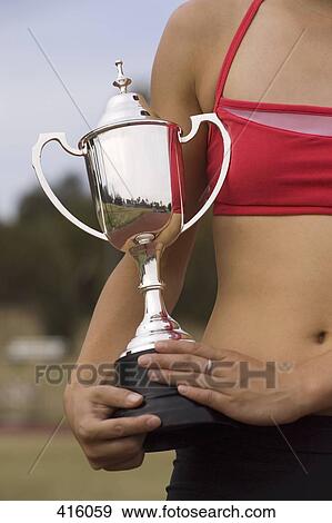 Stock Photo - Female athlete holding a trophy. Fotosearch