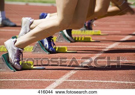 Female athletes with feet in starting blocks on a running track View Large Photo Image Picture - Female athletes with feet in starting blocks on a running track. Fotosearch