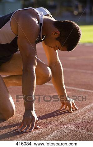 Picture - Male athlete in starting blocks on a running track. Fotosearch