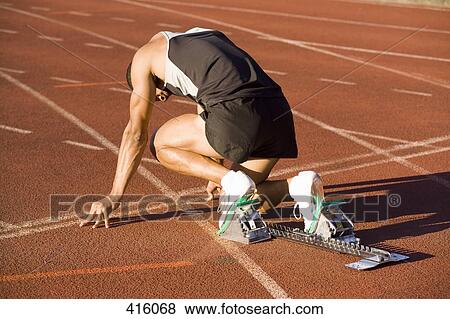 Stock Photo - Male athlete in starting blocks on a running track. Fotosearch
