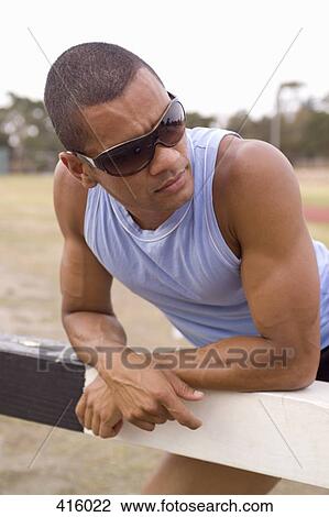 Stock Image - Male athlete stretching against a steeple. Fotosearch