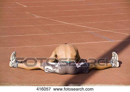 Stock Photo - Male athlete stretching next to a running track. Fotosearch