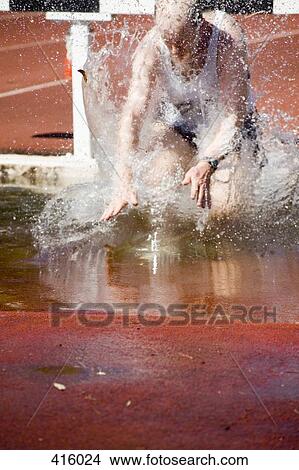 Picture - Man falling in water jump during steeplechase event. Fotosearch