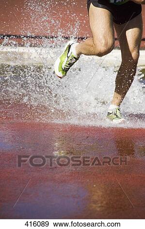 Man running through water jump during steeplechase event View Large Photo Image Stock Photo - Man running through water jump during steeplechase event. Fotosearch