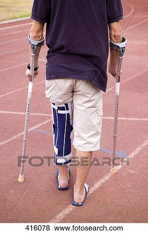 Stock Photo - Man with his leg in a brace and using crutches. Fotosearch