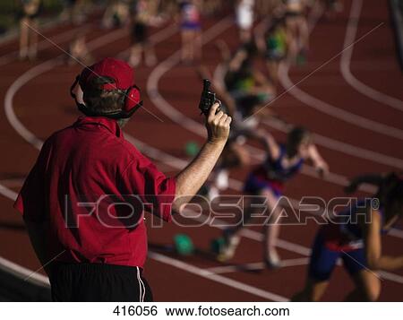 Stock Photograph - Race official holding a starting gun at the beginning of a track event. Fotosearch