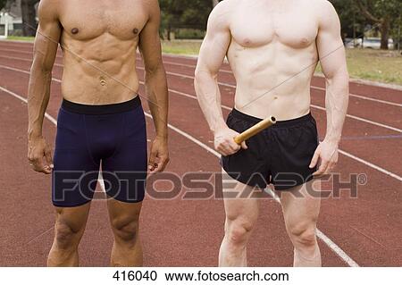 Stock Image - Two male athletes standing side by side on a running track. Fotosearch