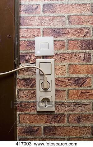 Stock Image - Electric plug and socket on a wall. Fotosearch