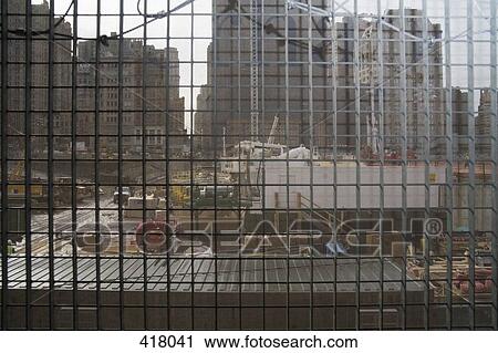 Stock Image - View through metal grid of construction site. Fotosearch