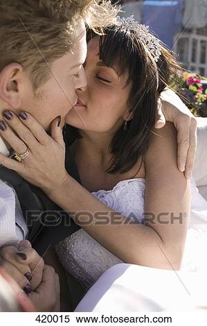Stock Photography - Bride and groom kissing in the back seat of a convertible car. Fotosearch