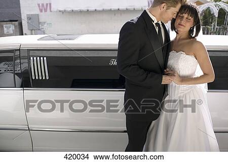 Bride and groom standing together in front of a stretch limousine View Large Photo Image Picture - Bride and groom standing together in front of a stretch limousine. Fotosearch