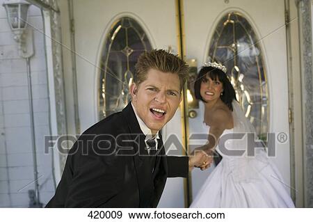 Stock Photo - Bride dragging groom into a wedding chapel. Fotosearch