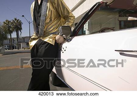 Elvis impersonator leaning against a vintage convertible car View Large Photo Image Stock Image - Elvis impersonator leaning against a vintage convertible car. Fotosearch