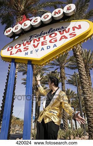 Elvis impersonator posing below the "Welcome to fabulous Las Vegas" sign View Large Photo Image Picture - Elvis impersonator posing below the "Welcome to fabulous Las Vegas" sign. Fotosearch